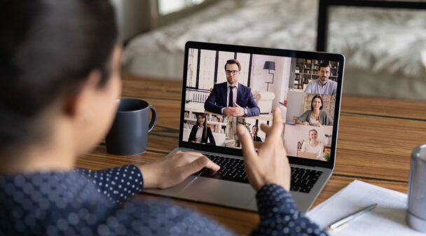 A person typing on a laptop with a coffee cup next to it.